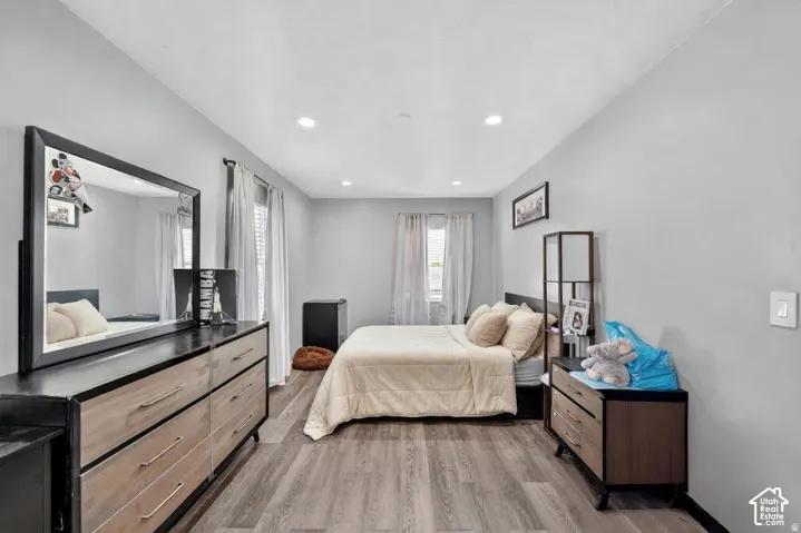 Spacious room featuring light gray walls, recessed lighting, wood-finish flooring, and multiple windows with blinds