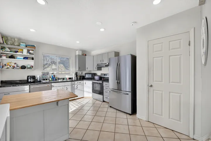 Kitchen featuring an island with a wood countertop, tile flooring, recessed lighting, and stainless steel appliances
