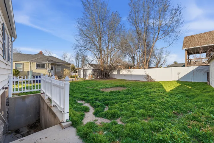Expansive backyard with a level lawn, secured by a white privacy fence