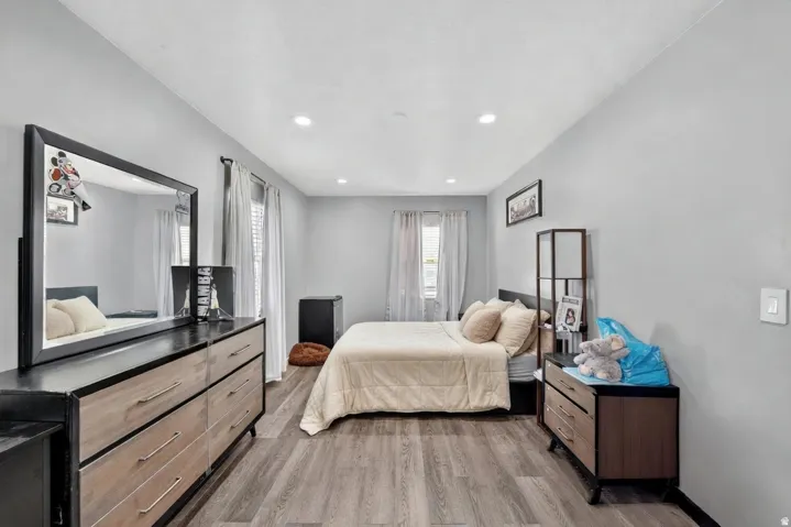 Spacious room featuring light gray walls, recessed lighting, wood-finish flooring, and multiple windows with blinds