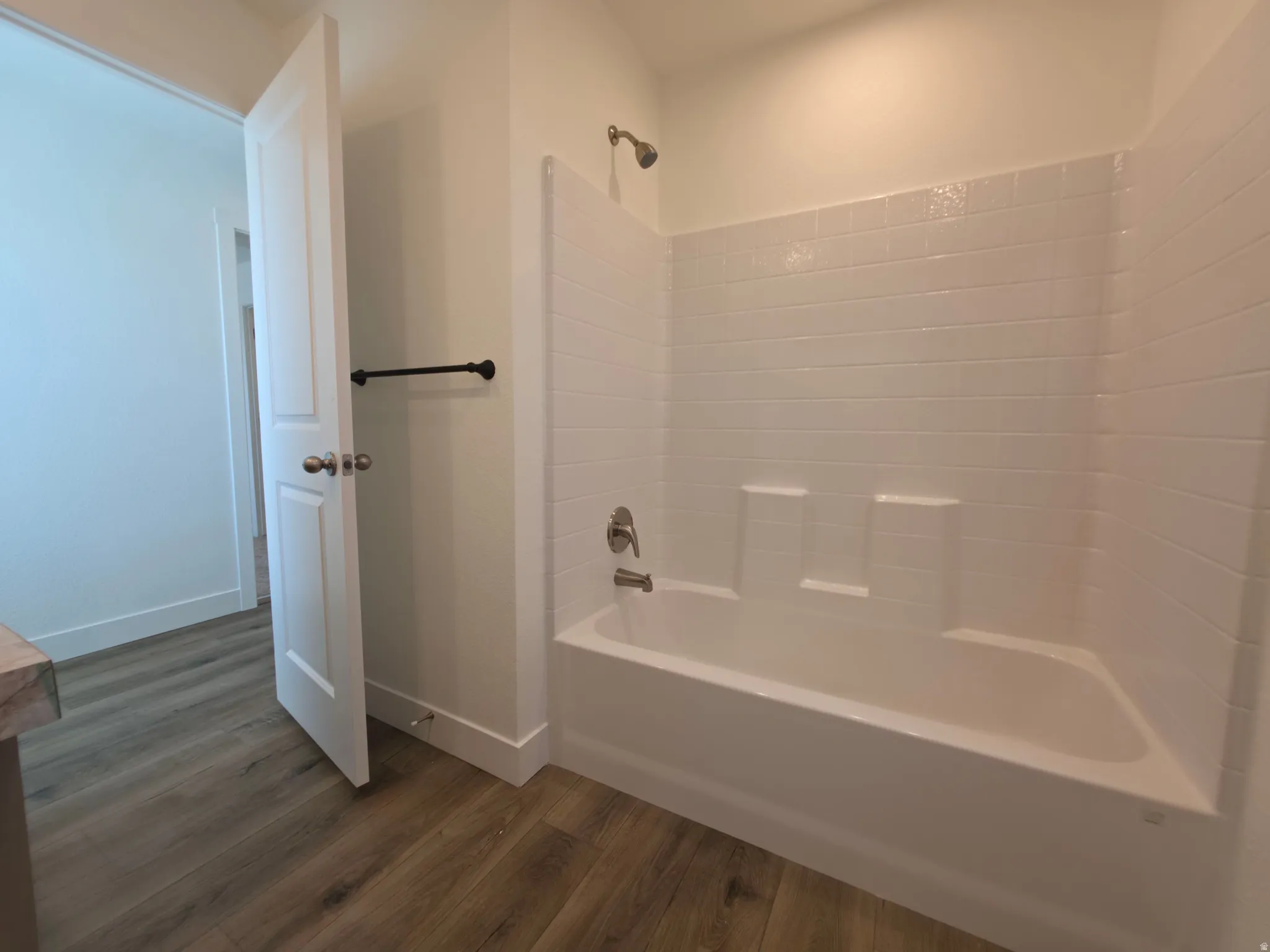 Full bathtub and shower combination with white subway tile surround and integrated shelving