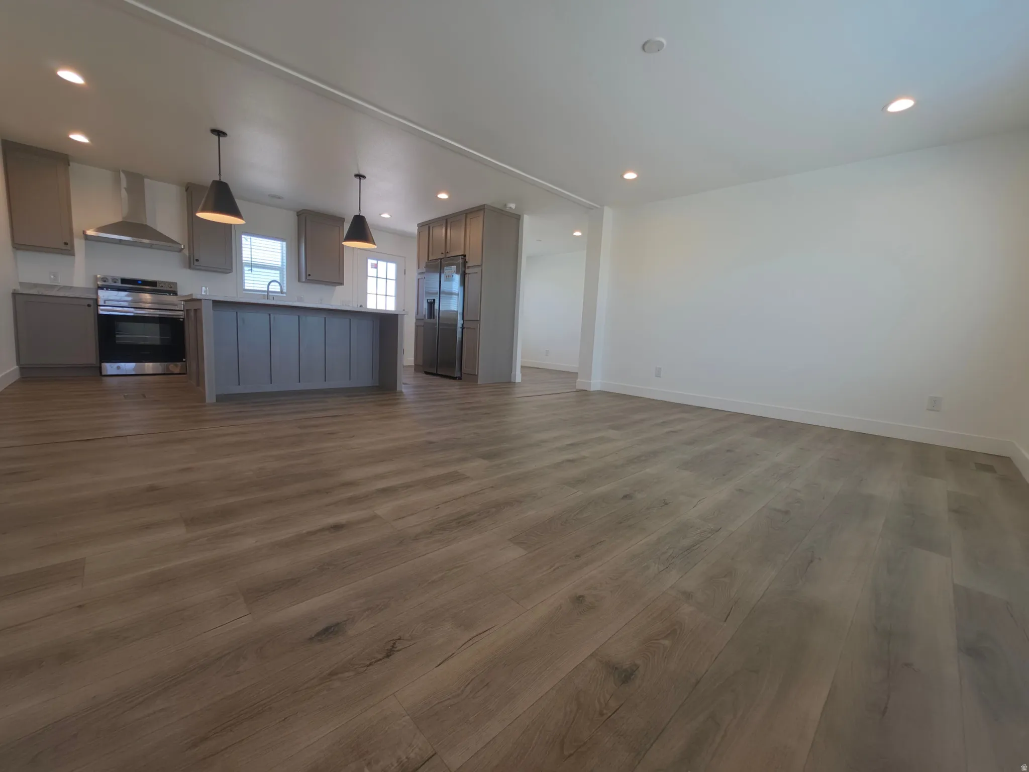 Open-concept living space featuring wood-finish flooring, recessed lighting, and a neutral color palette