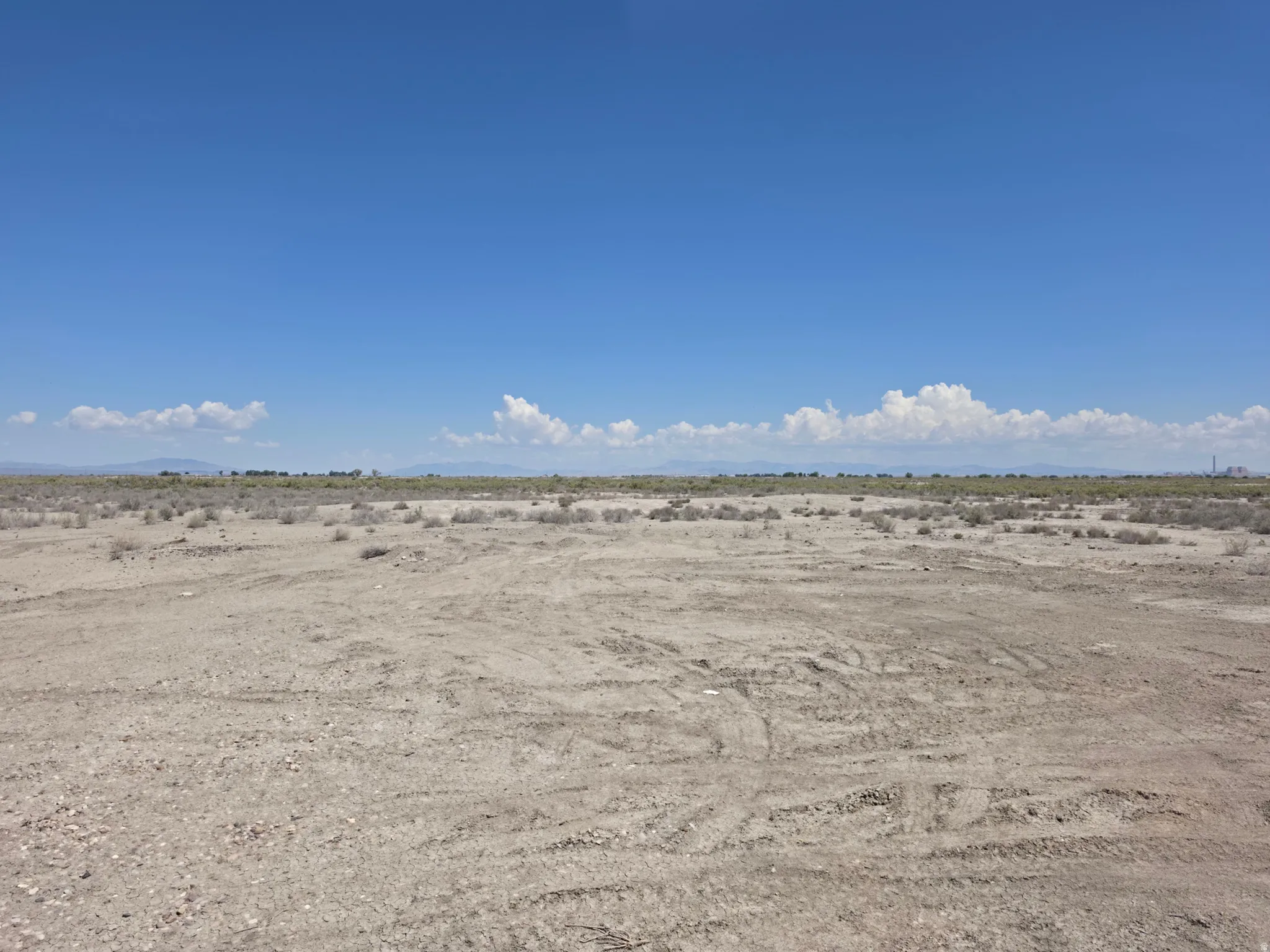 Expansive undeveloped land featuring a clear sky overhead and distant mountains