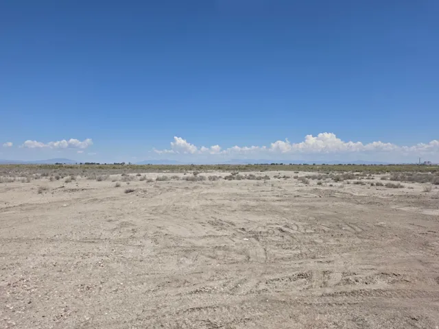 Expansive undeveloped land featuring a clear sky overhead and distant mountains