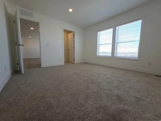Carpeted room featuring two prominent windows with blinds, recessed lighting, and white trim
