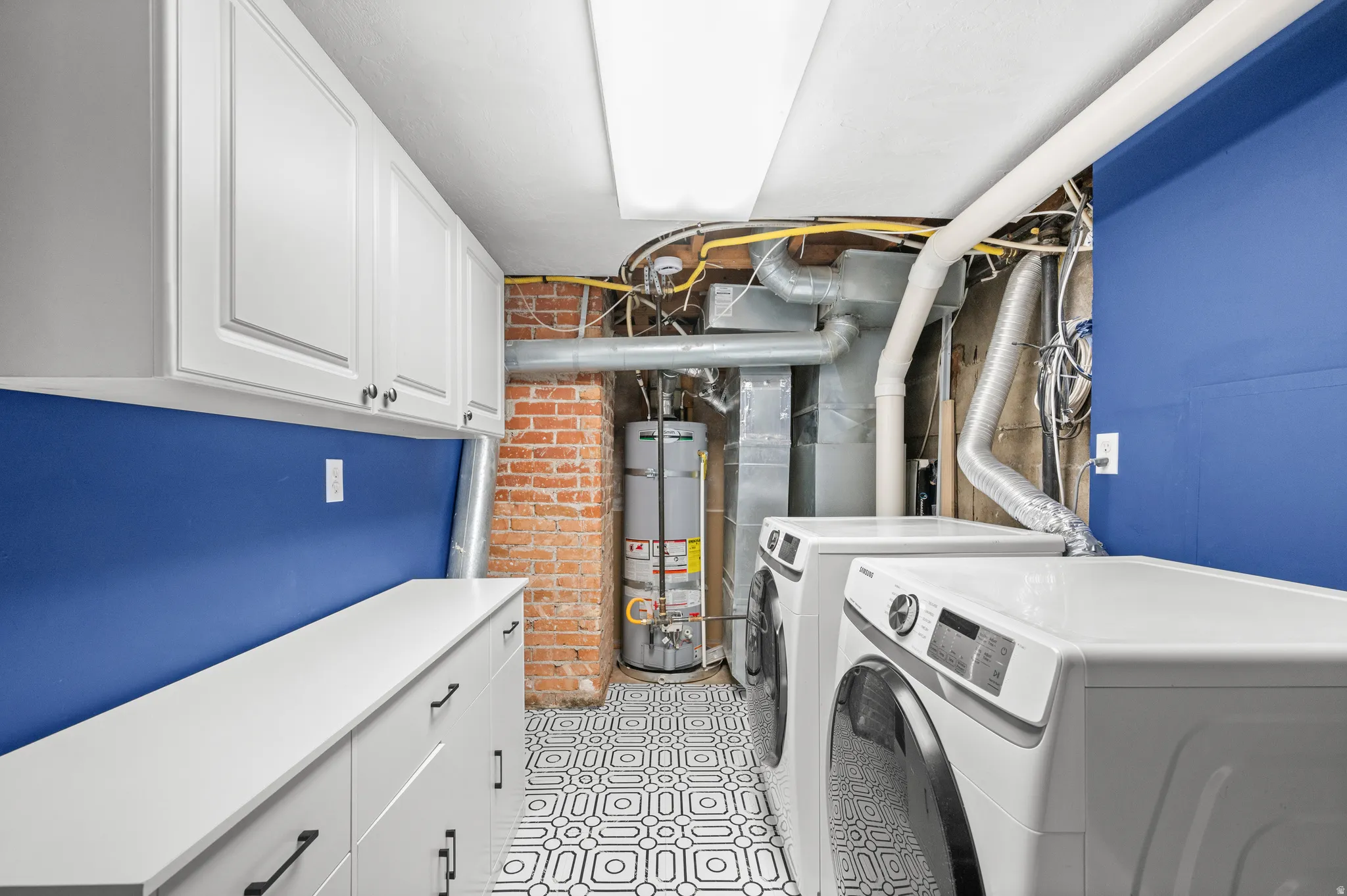 Laundry area featuring white cabinetry, a white countertop, and patterned floor tiles