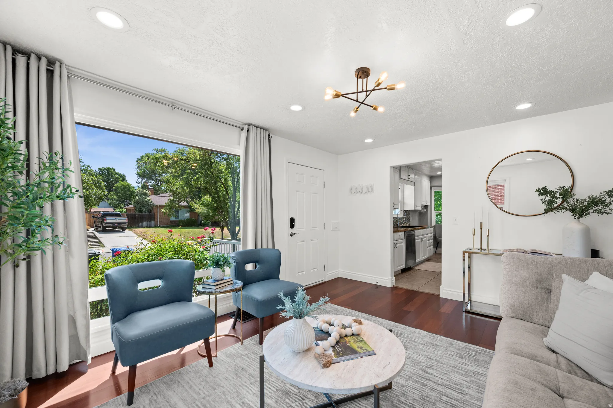 Bright living space featuring a large picture window, recessed lighting, and rich wood-finish flooring