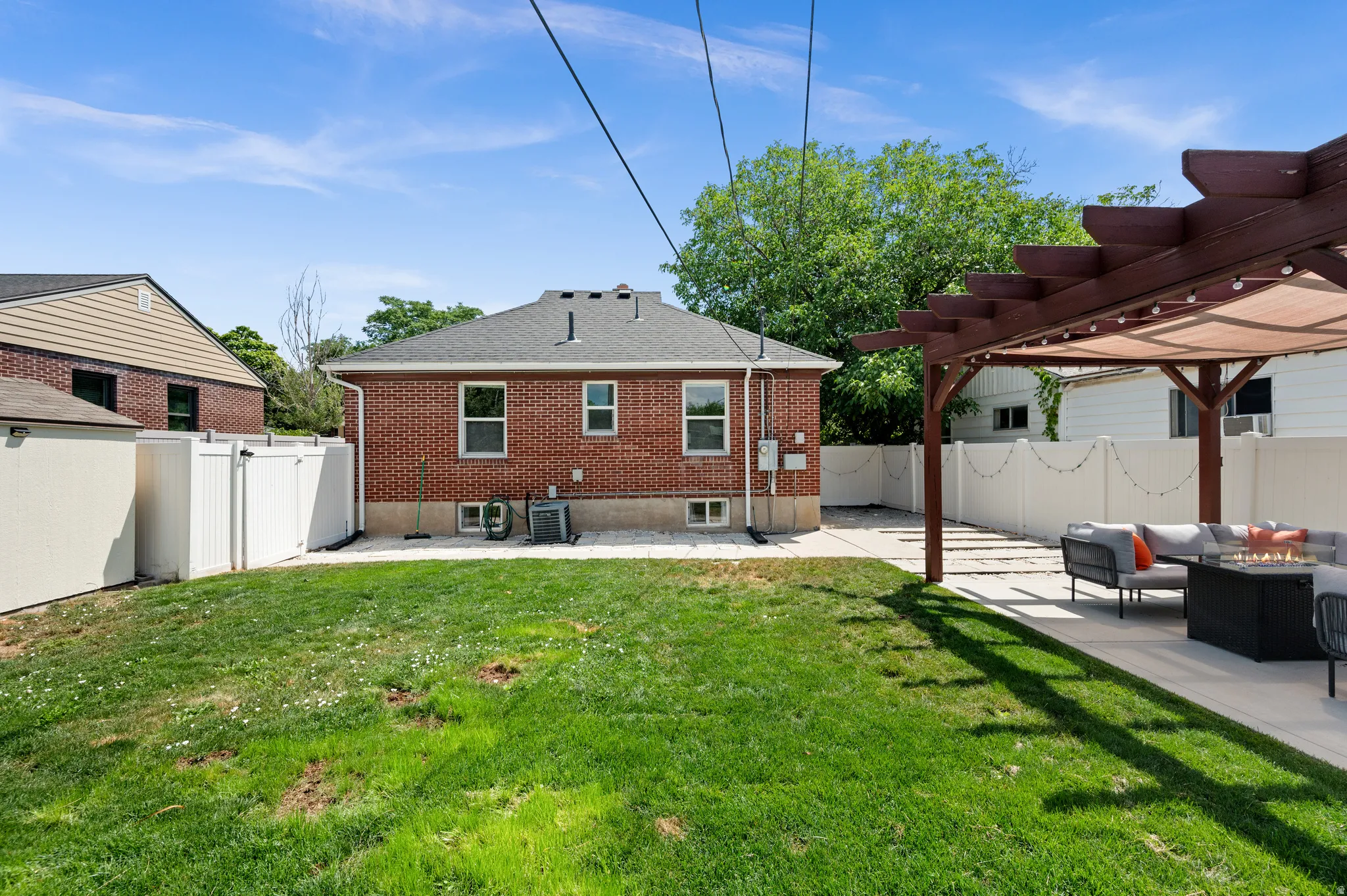 Expansive backyard featuring a manicured lawn, a large pergola with a retractable shade cover, and a spacious paver patio