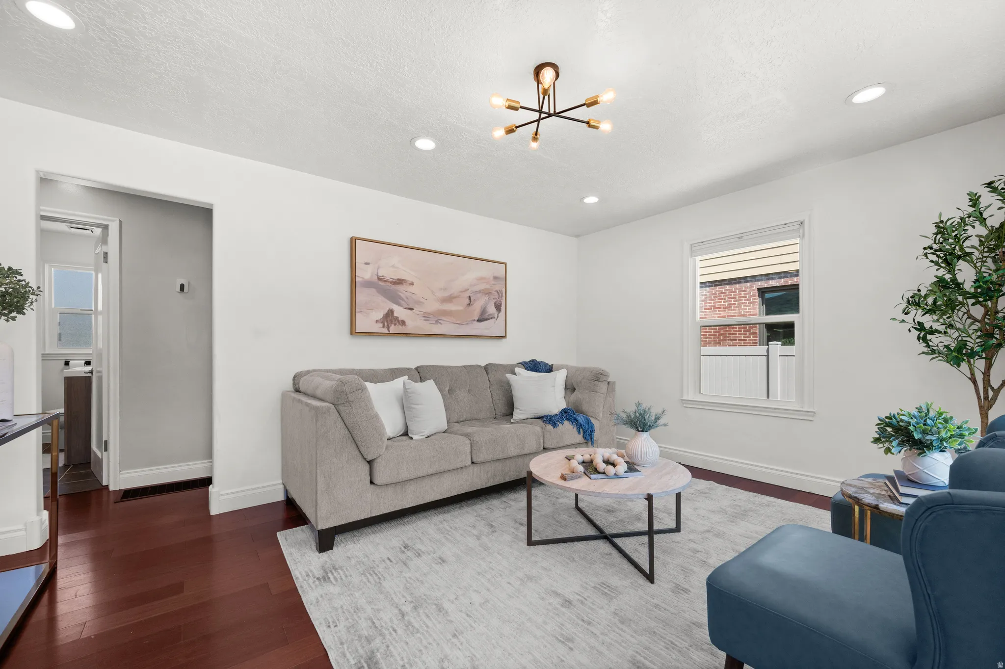 Living area featuring rich wood-finish flooring, white baseboards, and bright recessed lighting