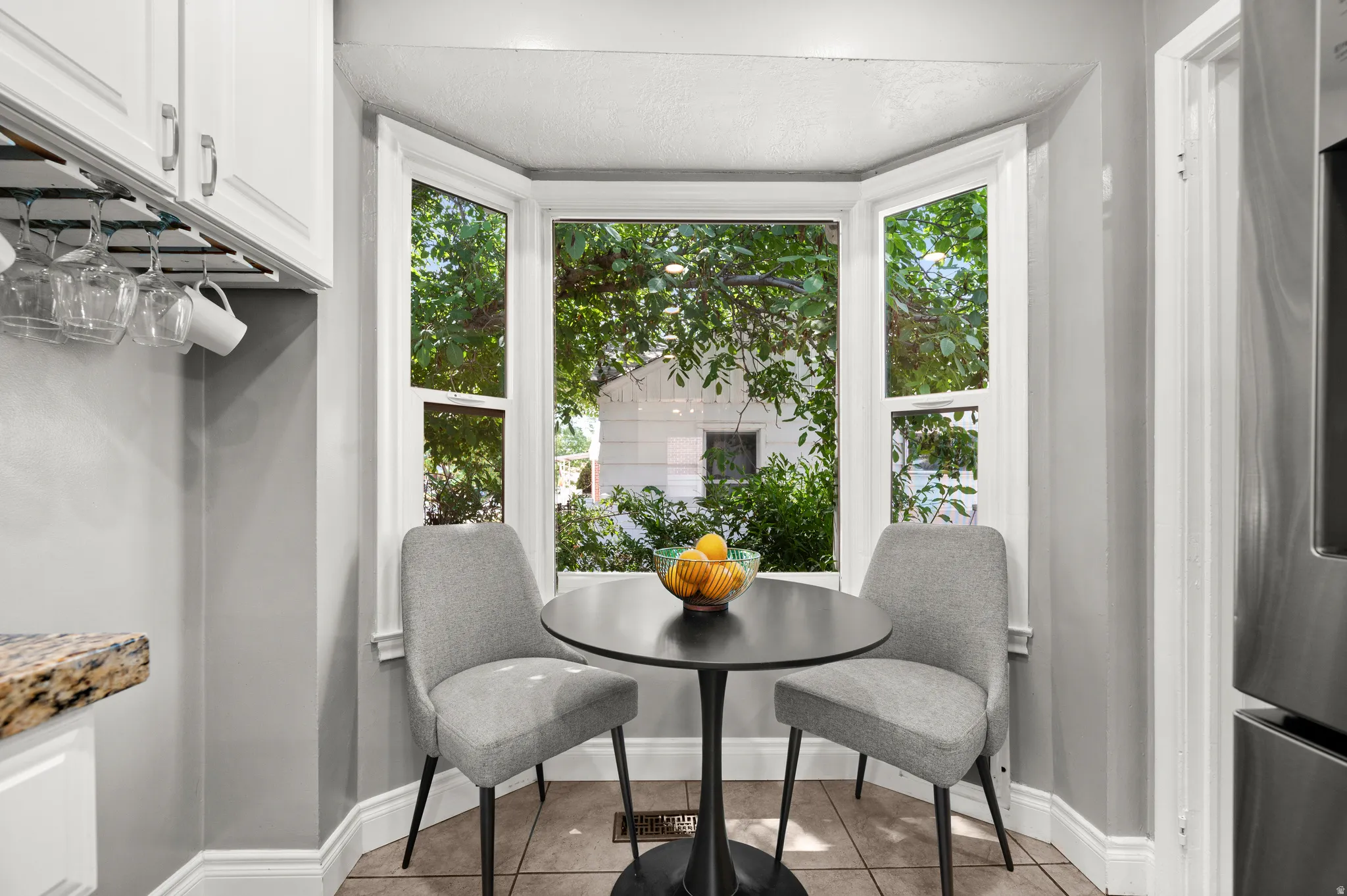 Kitchen nook featuring a three-panel bay window, white cabinetry, and a stone countertop