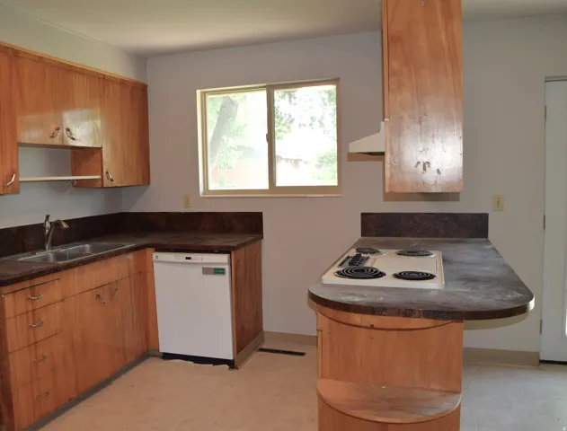 Kitchen featuring wood-finish cabinetry, a double basin stainless steel sink, and a built-in dishwasher