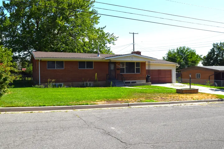 Brick ranch-style home featuring a covered front entry, attached two-car garage with dual doors, and a front yard with established landscaping