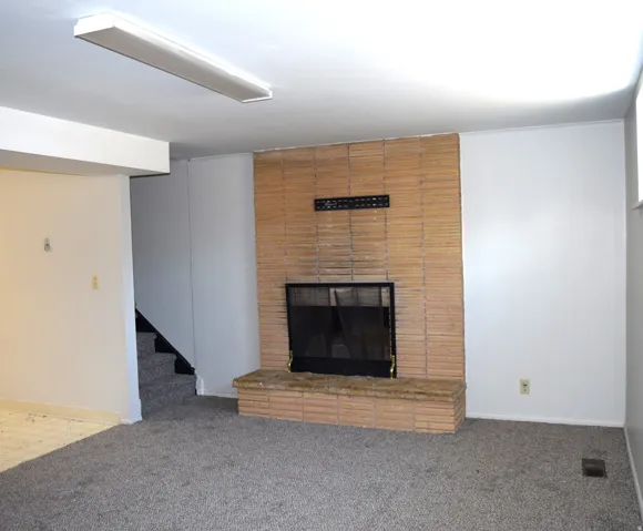 Brick-faced fireplace with a black metal screen, flanked by white walls