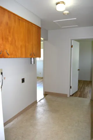 Laundry area featuring overhead wood cabinetry, a utility hookup, and neutral-toned flooring