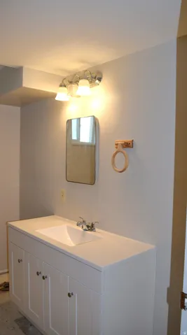 White vanity with four cabinet doors, an integrated sink, and a chrome-finish faucet