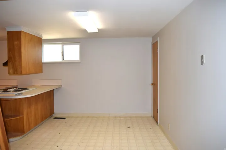 Kitchen area with wood-finish cabinetry, light-toned countertop, and patterned vinyl flooring