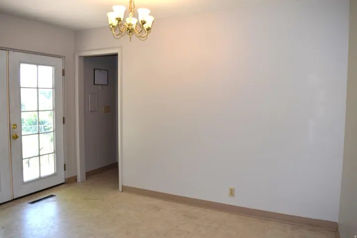 Room featuring light-colored flooring, white walls, and a gold-tone chandelier with frosted glass shades