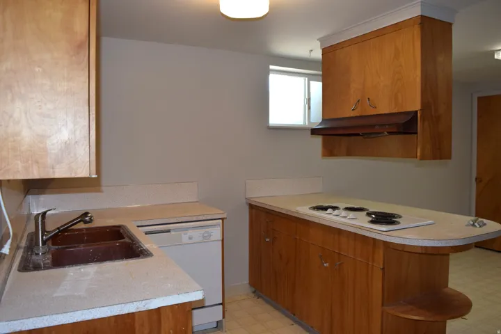 Kitchen featuring wood cabinetry, integrated cooktop, a built-in dishwasher, and a double basin sink