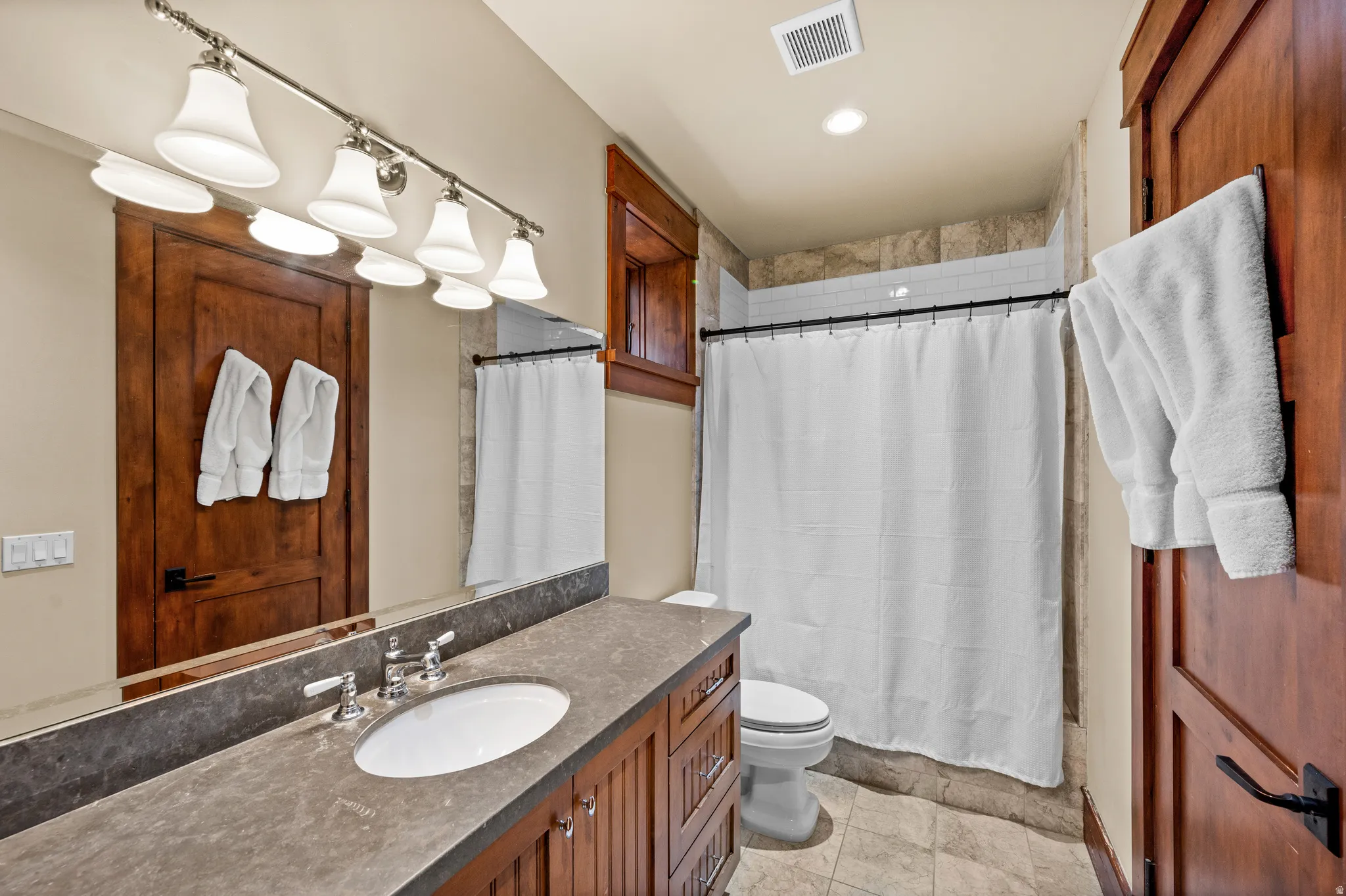 Bathroom featuring a double vanity with an integrated sink, polished chrome fixtures, and a stone-finish countertop