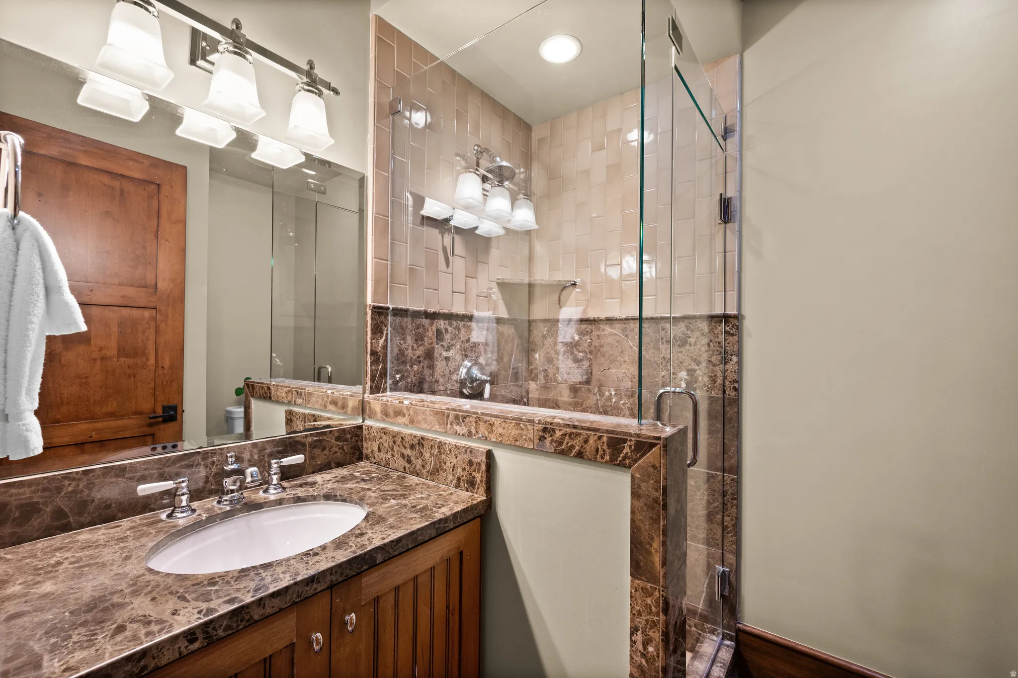 Bathroom vanity with a polished stone countertop featuring an undermount sink and a chrome faucet