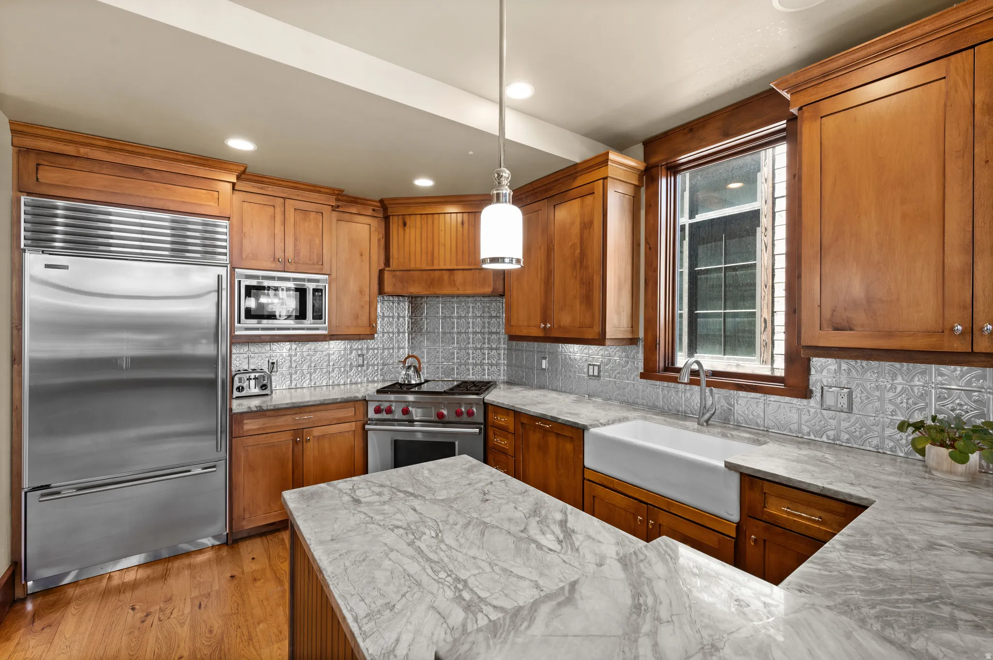 Gourmet kitchen featuring a stainless steel refrigerator, professional-grade range, farmhouse sink, wood cabinetry, and patterned backsplash