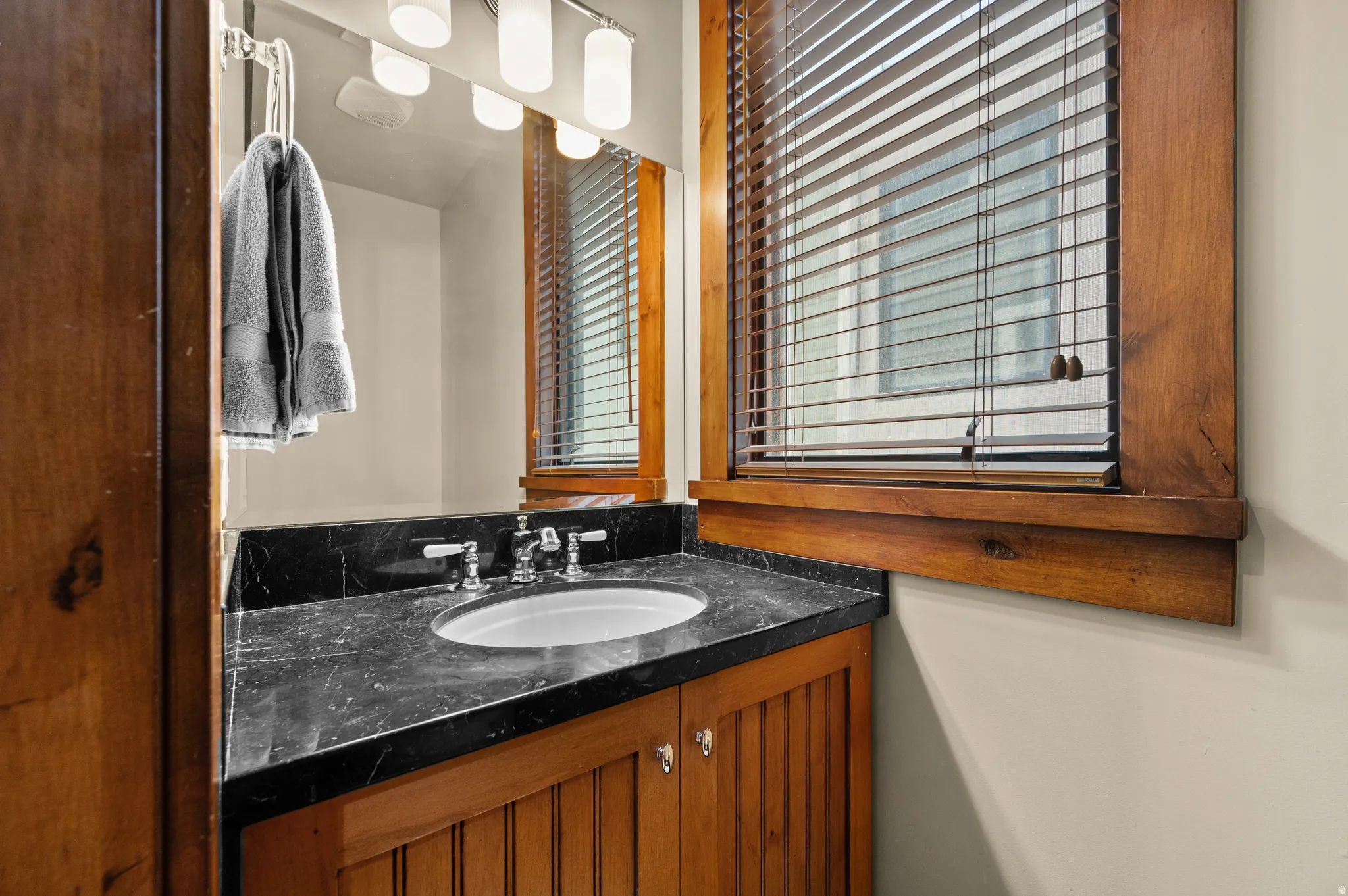 Bathroom vanity with a dark countertop, undermount sink, and chrome-finish faucet