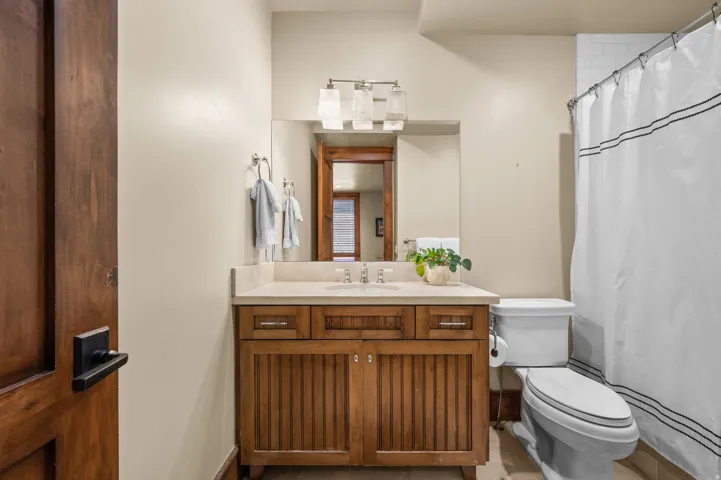 Bathroom featuring a wooden vanity with a light-toned countertop, an undermount sink, and a modern light fixture