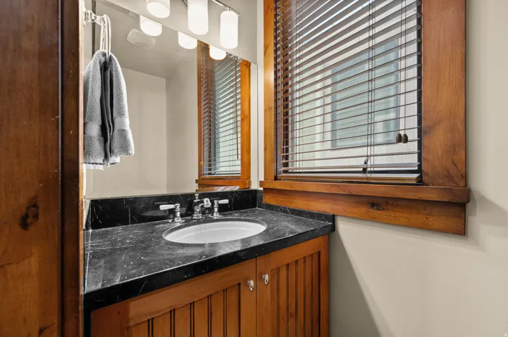 Bathroom vanity with a dark countertop, undermount sink, and chrome-finish faucet