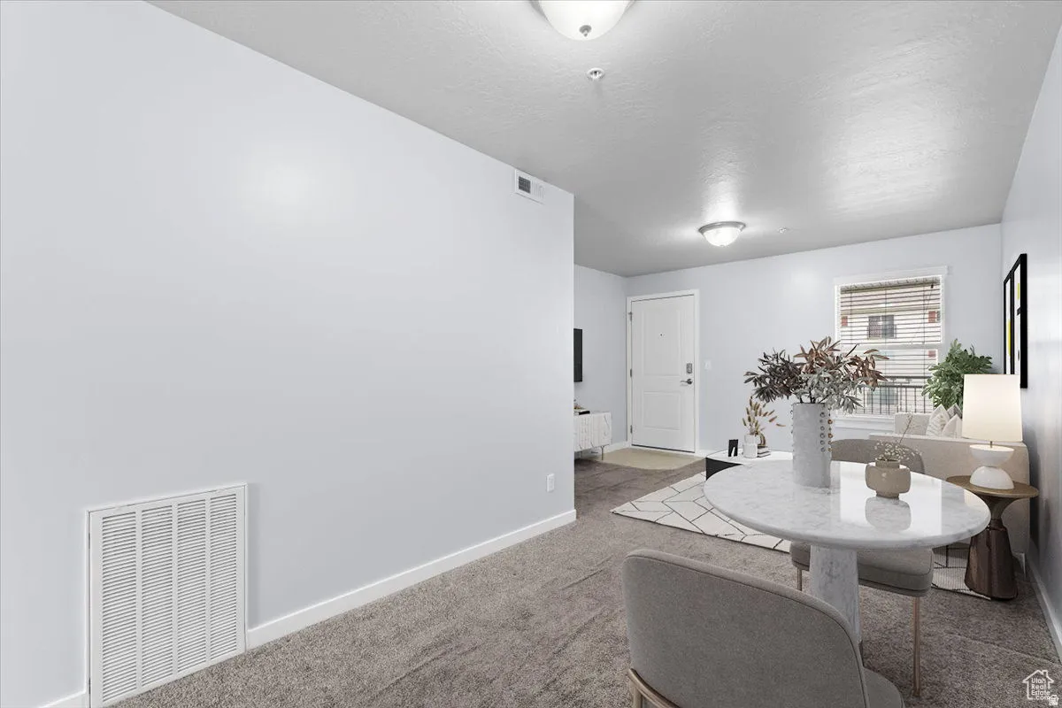 Open-concept living space with light gray walls, plush gray carpeting, and white trim