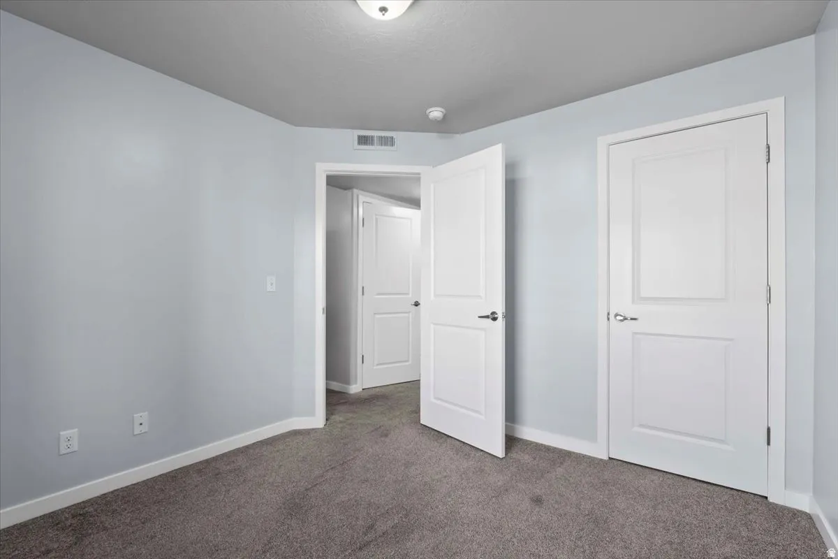 Carpeted interior room featuring light blue walls, white baseboards, and white two-panel doors with brushed nickel hardware