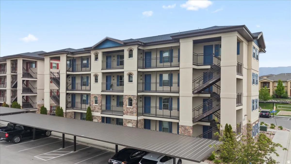 Multi-story residential building featuring a neutral stucco exterior with contrasting stone accents