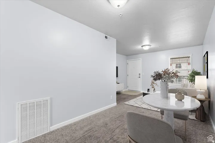 Open-concept living space with light gray walls, plush gray carpeting, and white trim