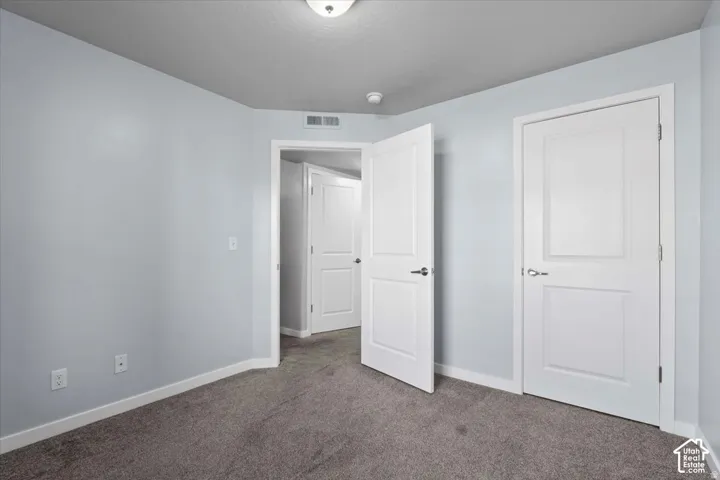 Carpeted interior room featuring light blue walls, white baseboards, and white two-panel doors with brushed nickel hardware