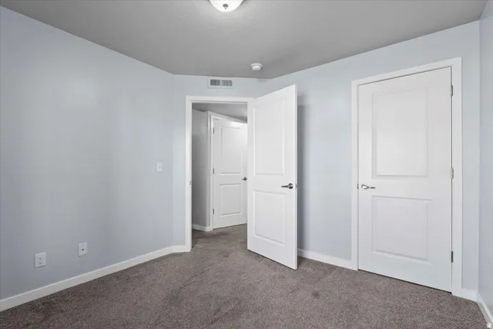 Carpeted interior room featuring light blue walls, white baseboards, and white two-panel doors with brushed nickel hardware
