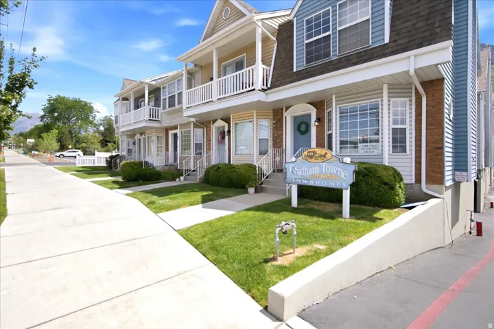 Townhome exterior featuring blue and tan siding with white trim, multiple bay windows, and a covered front porch with white railings