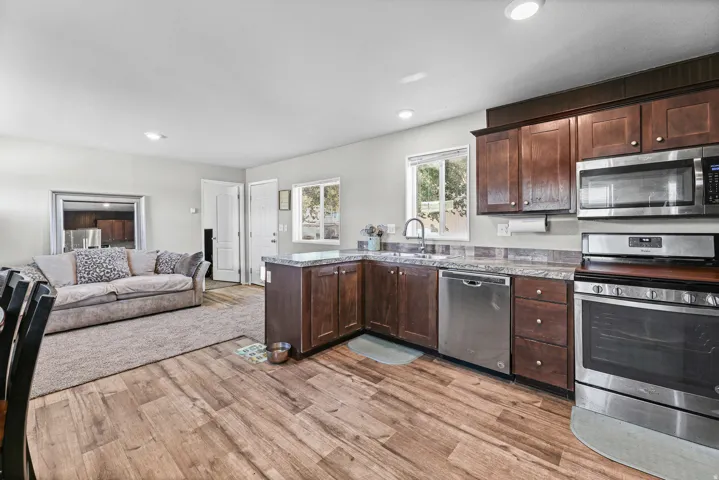 Kitchen featuring wood-finish flooring, dark wood cabinetry, stainless steel appliances, and a window above the sink