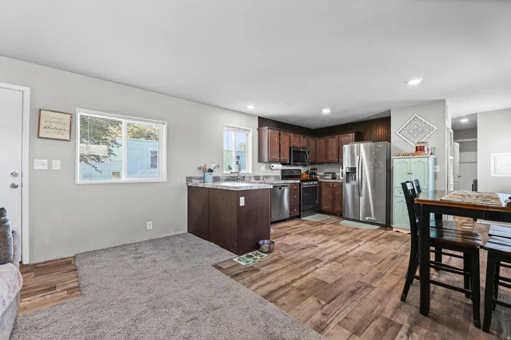 Open-concept kitchen and dining area featuring rich wood-finish cabinetry, stainless steel appliances, and wood-finish flooring throughout the kitchen and dining spaces