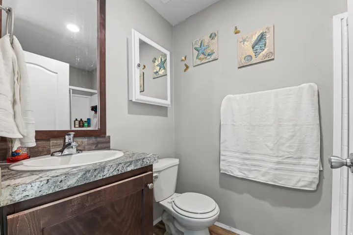Bathroom featuring a single vanity with wood-finish cabinetry, a patterned countertop, and an oval undermount sink