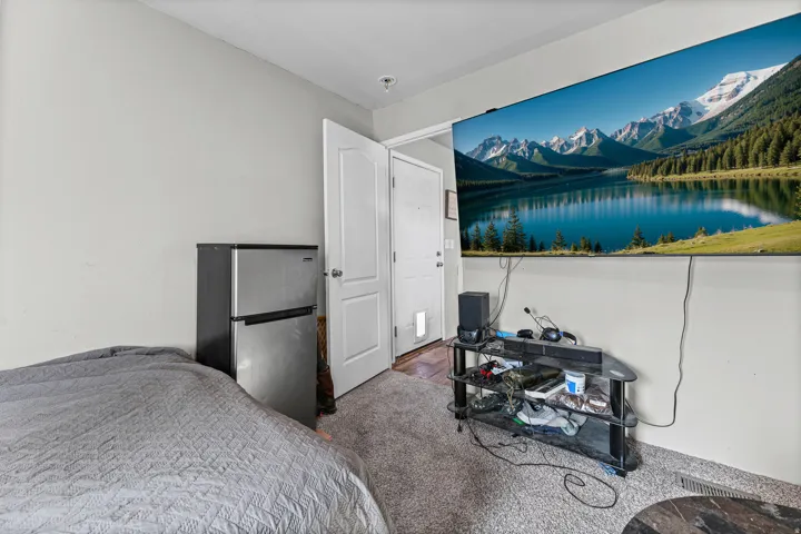 Carpeted room with light gray walls, a white paneled door, and a wall-mounted television