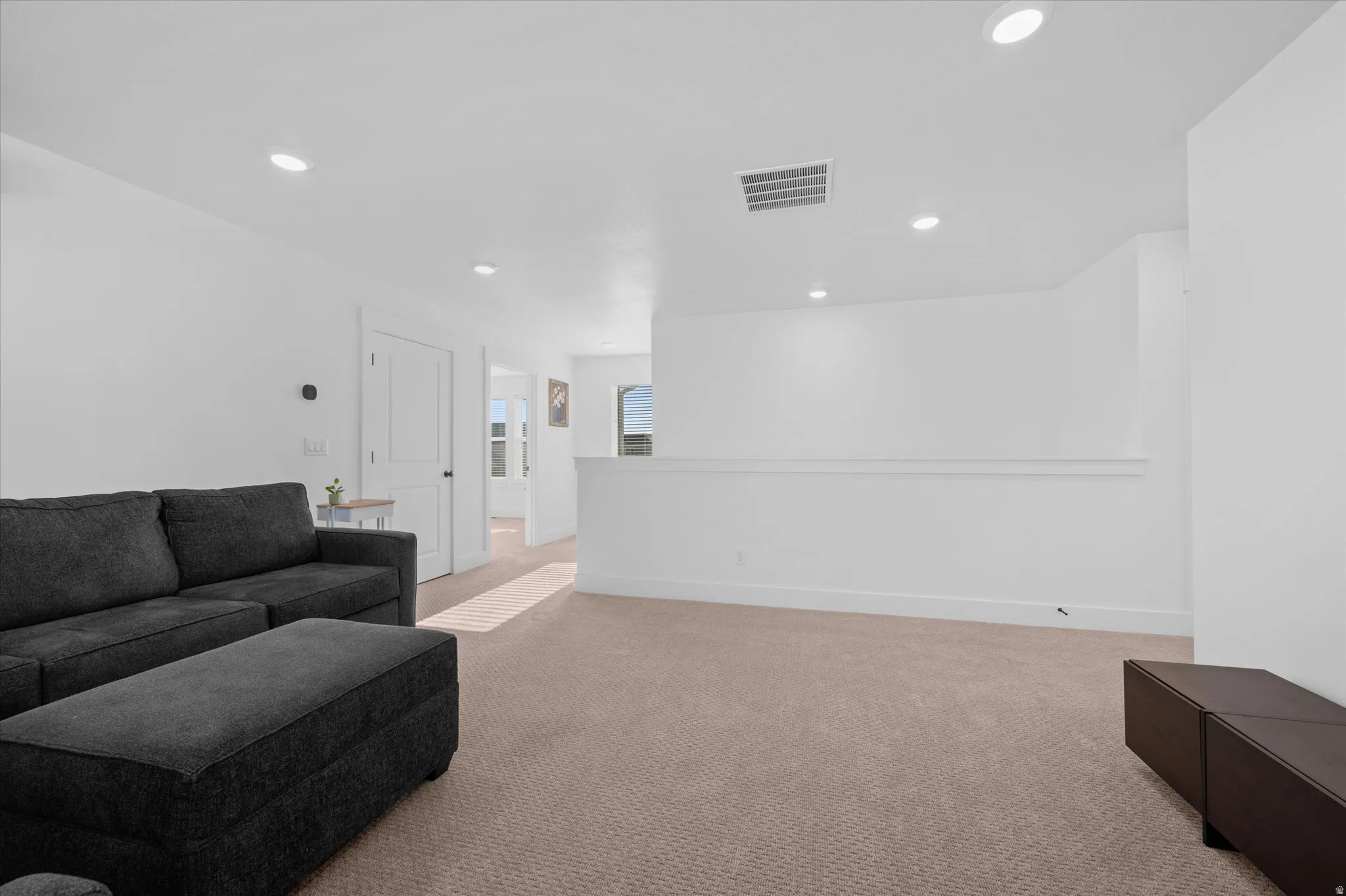 Recessed lighting, light neutral-toned carpet flooring, white walls, white trim, and a white interior door