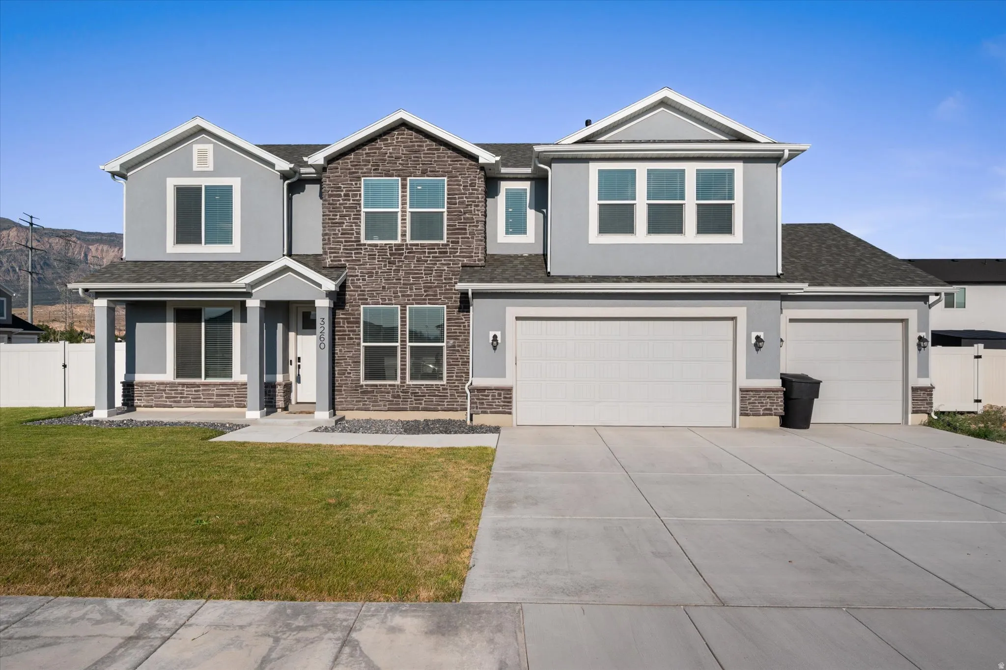 Stucco and stone exterior with gabled roof lines, multiple windows, an attached two-car garage, and an additional attached single-car garage