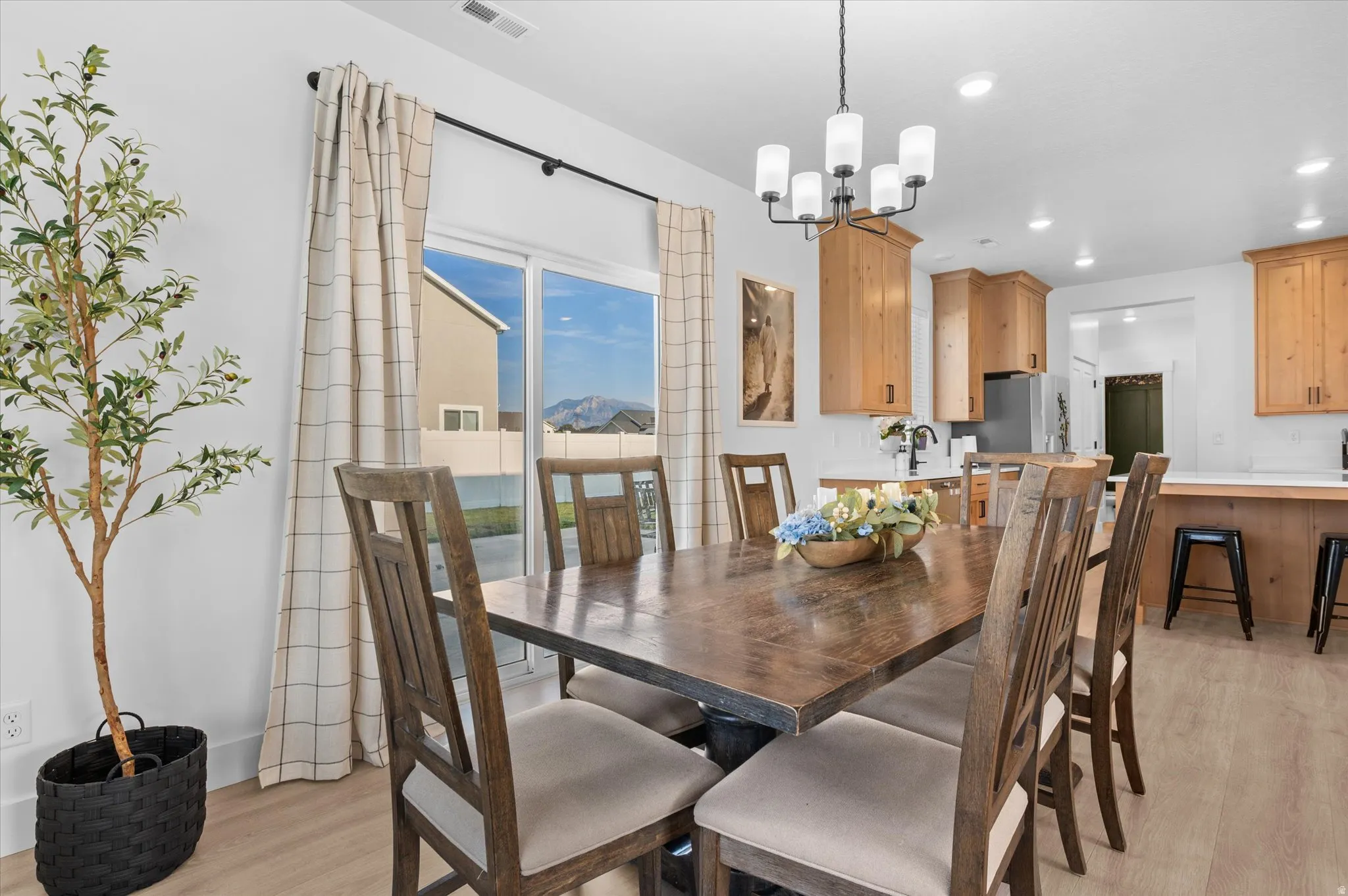 Open-concept living area featuring a multi-light chandelier, light wood-finish flooring, a sliding glass door, and recessed lighting