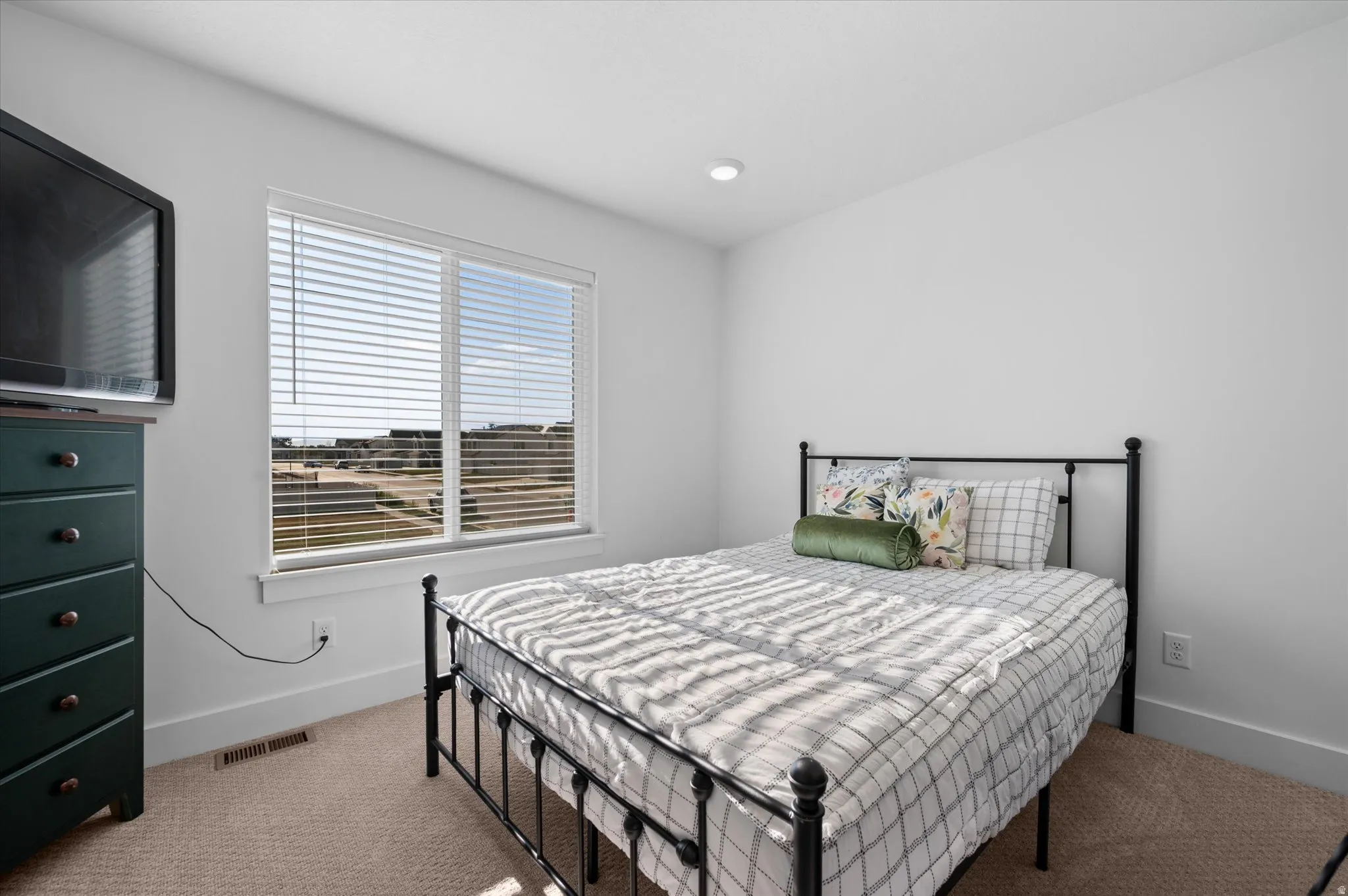 Recessed lighting, large window with blinds, and neutral carpeting