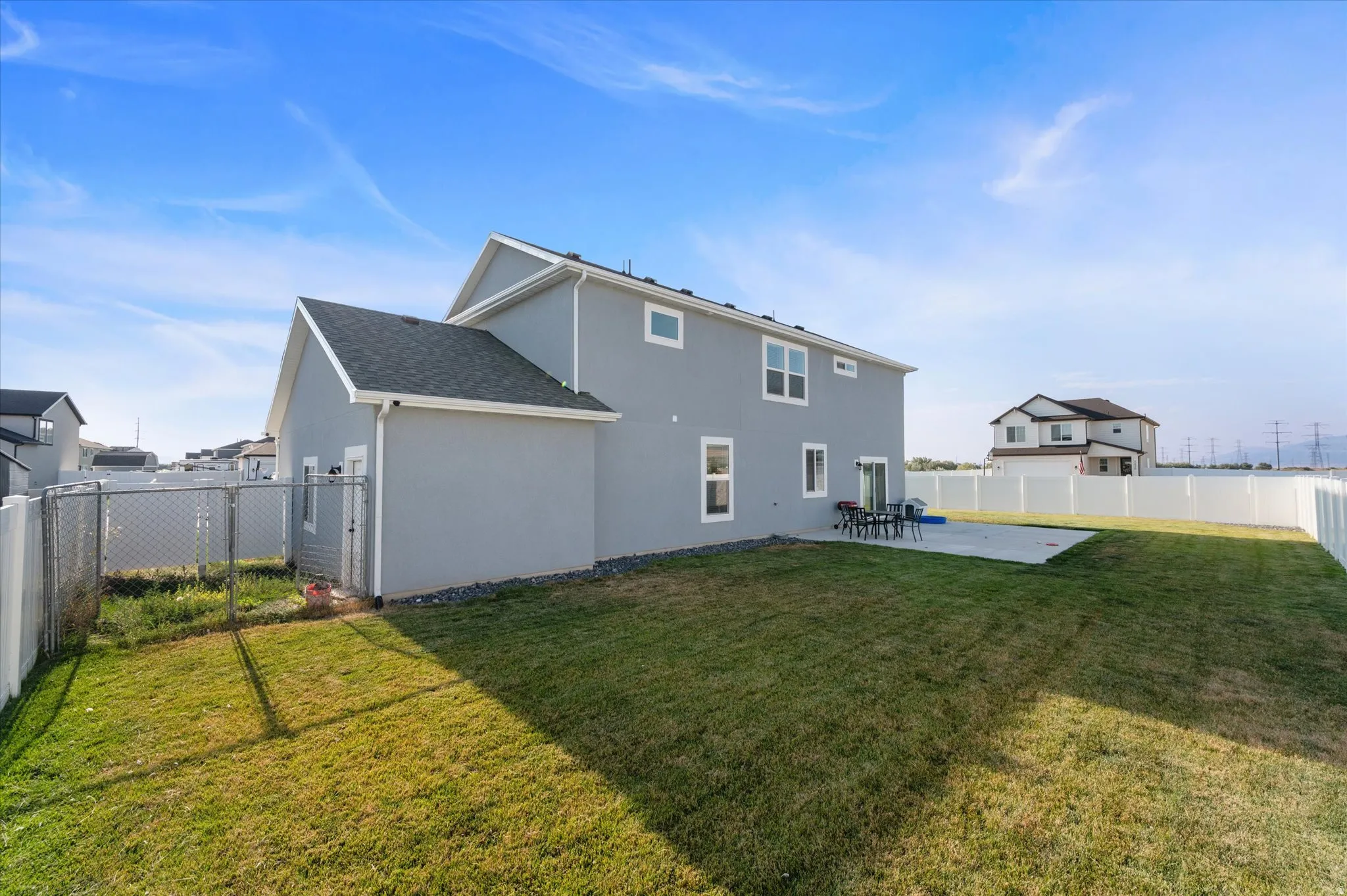 Spacious backyard with a concrete patio, expansive lawn, and a chain-link fence