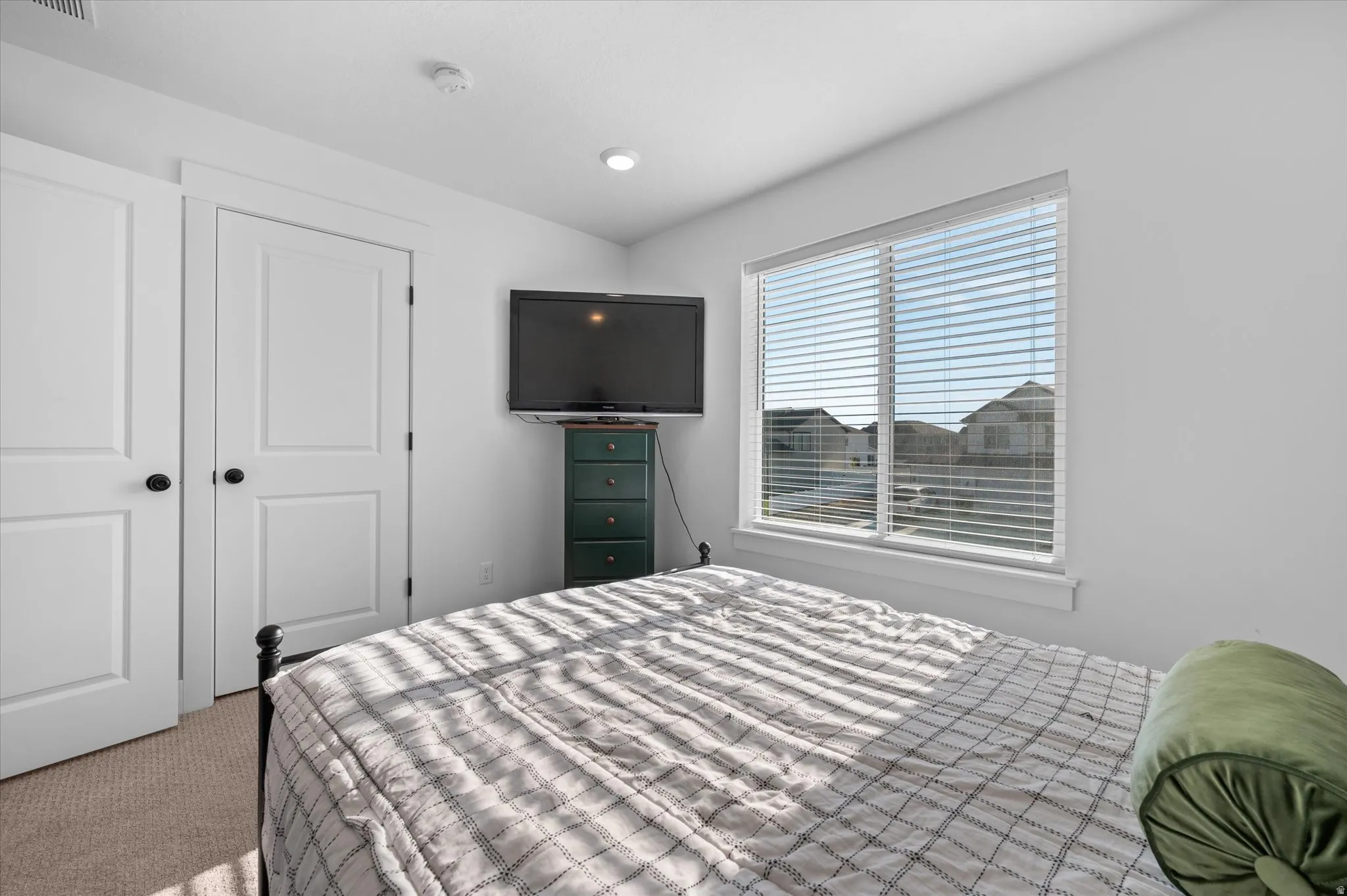Recessed ceiling lighting, white interior doors with black hardware, and a large window with blinds