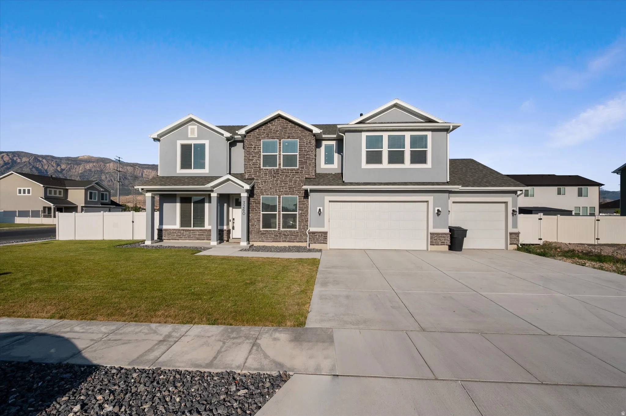 Two-story residence featuring a combination of light gray siding and stone veneer