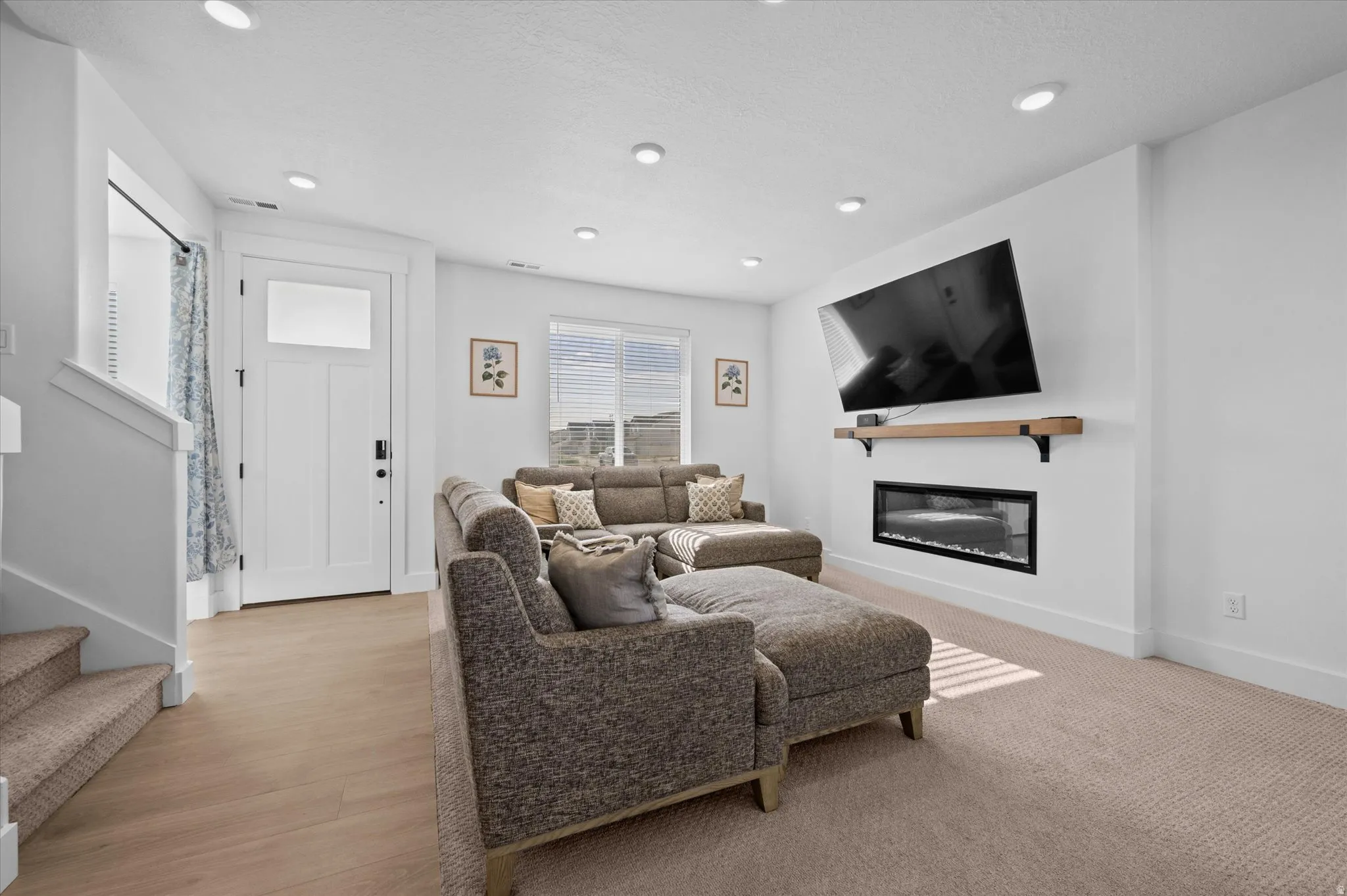 Recessed lighting, wood-finish flooring, white walls, built-in electric fireplace with mantel, and large window