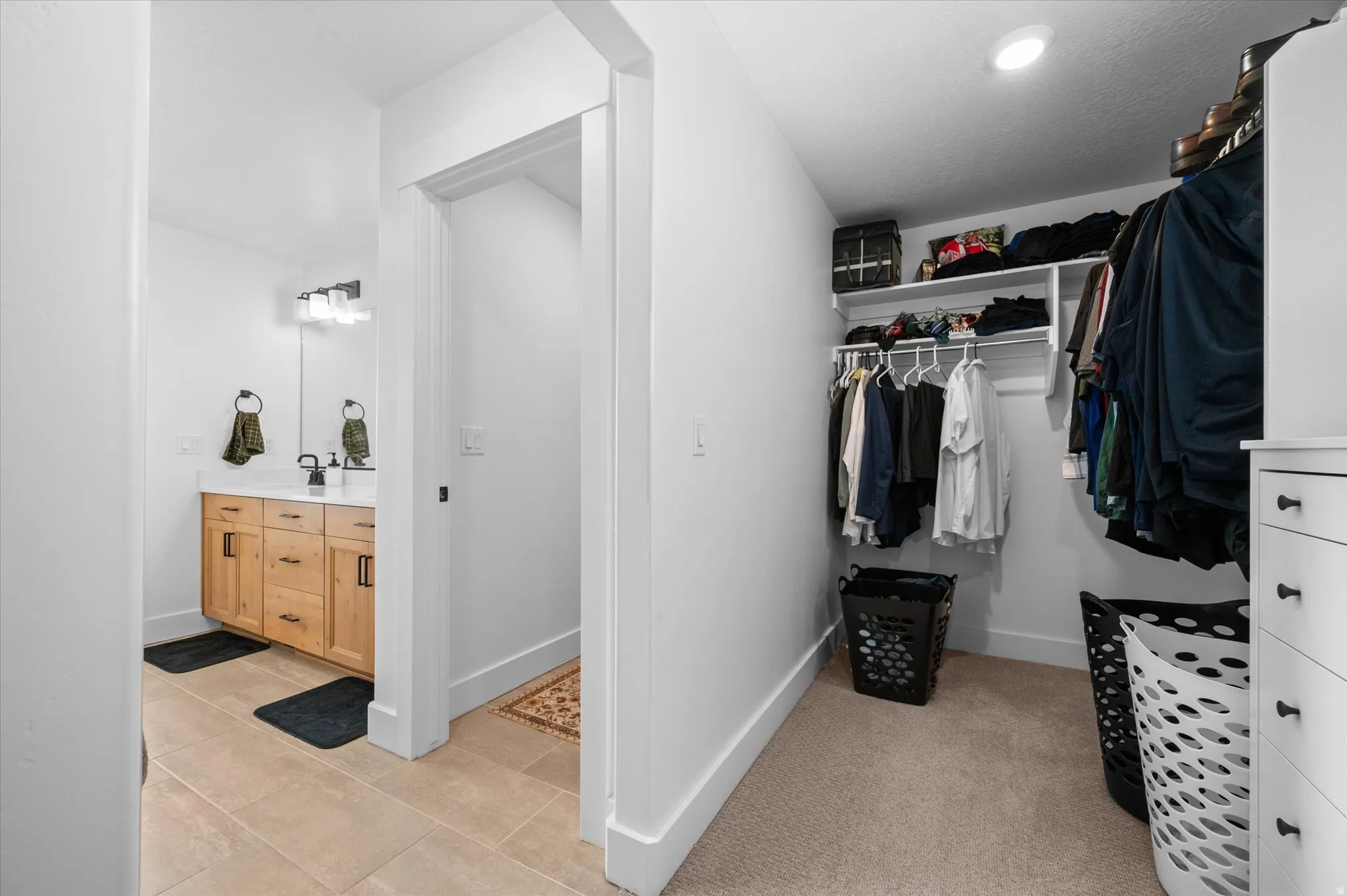 Bathroom with a wood-finish vanity, white countertop, and rectangular mirror