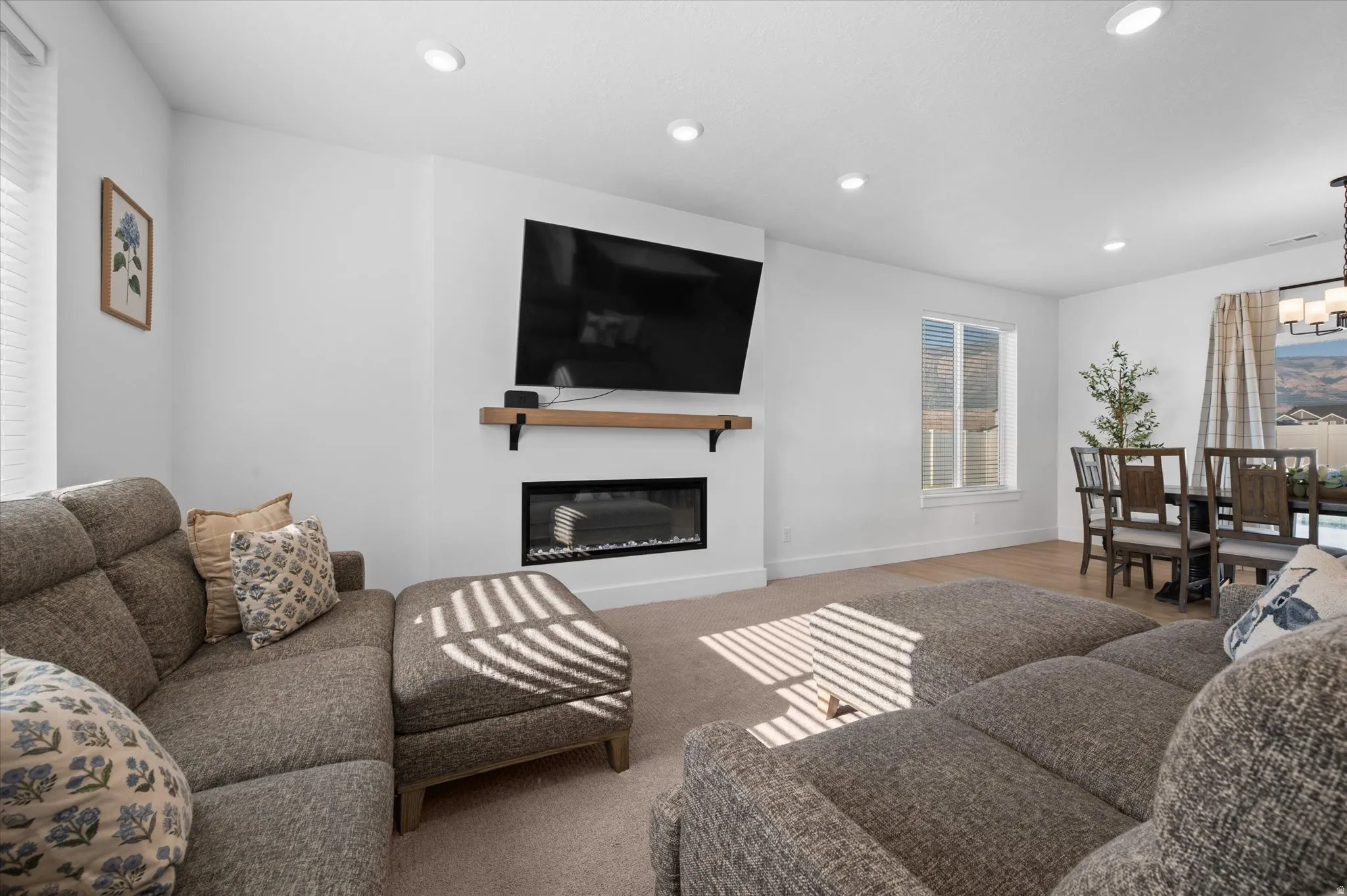 Recessed lighting, electric fireplace, wood mantel, and a dining area with a chandelier