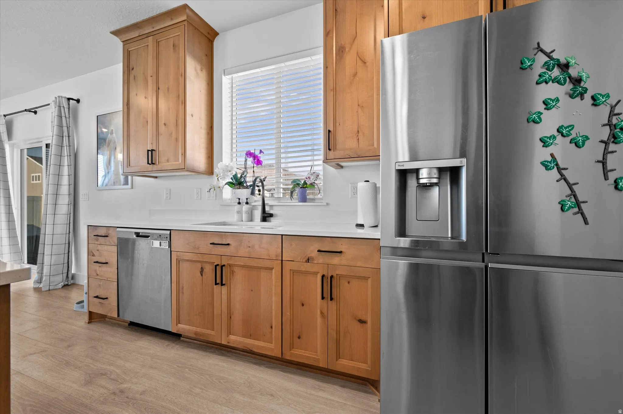 Kitchen featuring wood cabinetry, stainless steel appliances, white countertops, and wood-finish flooring